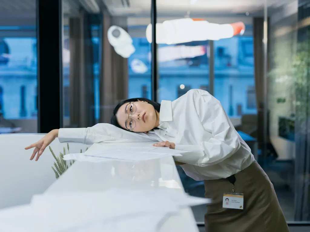 Illustration showing reduced productivity. In the photo there is a tired and bored woman, who is an office worker. The woman lies on the desk and looks at the ceiling.