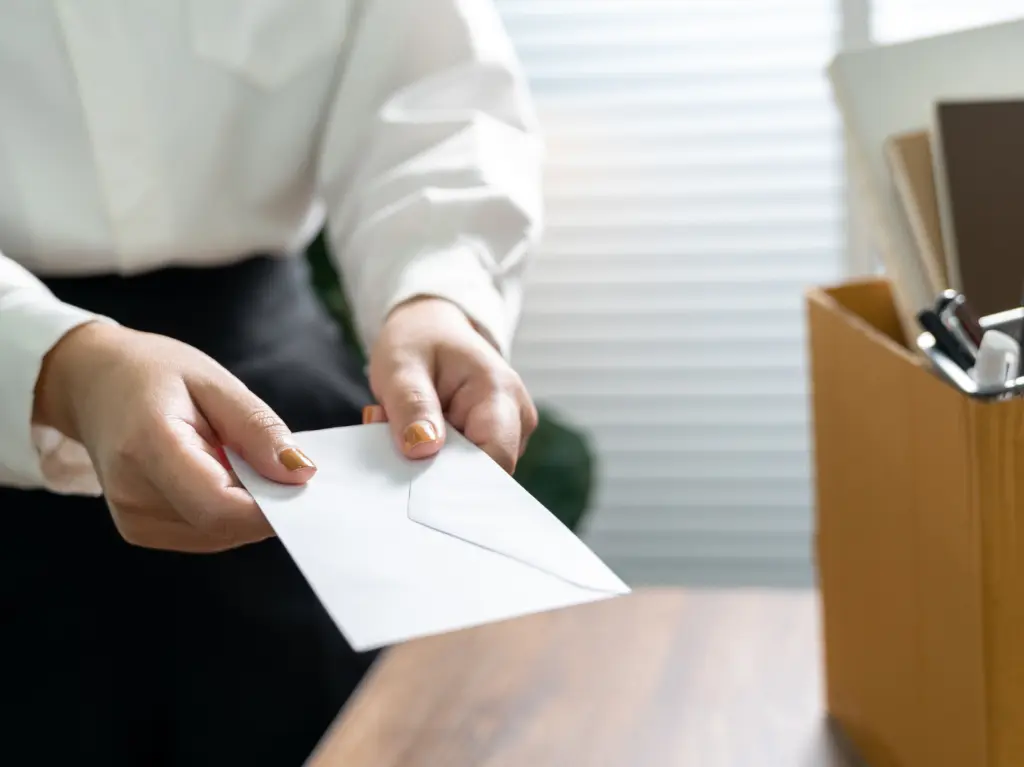 Illustration showing increased employee turnover. A woman, an office worker, hands a white envelope - a notice of termination, next to it there is a packed carton of things.